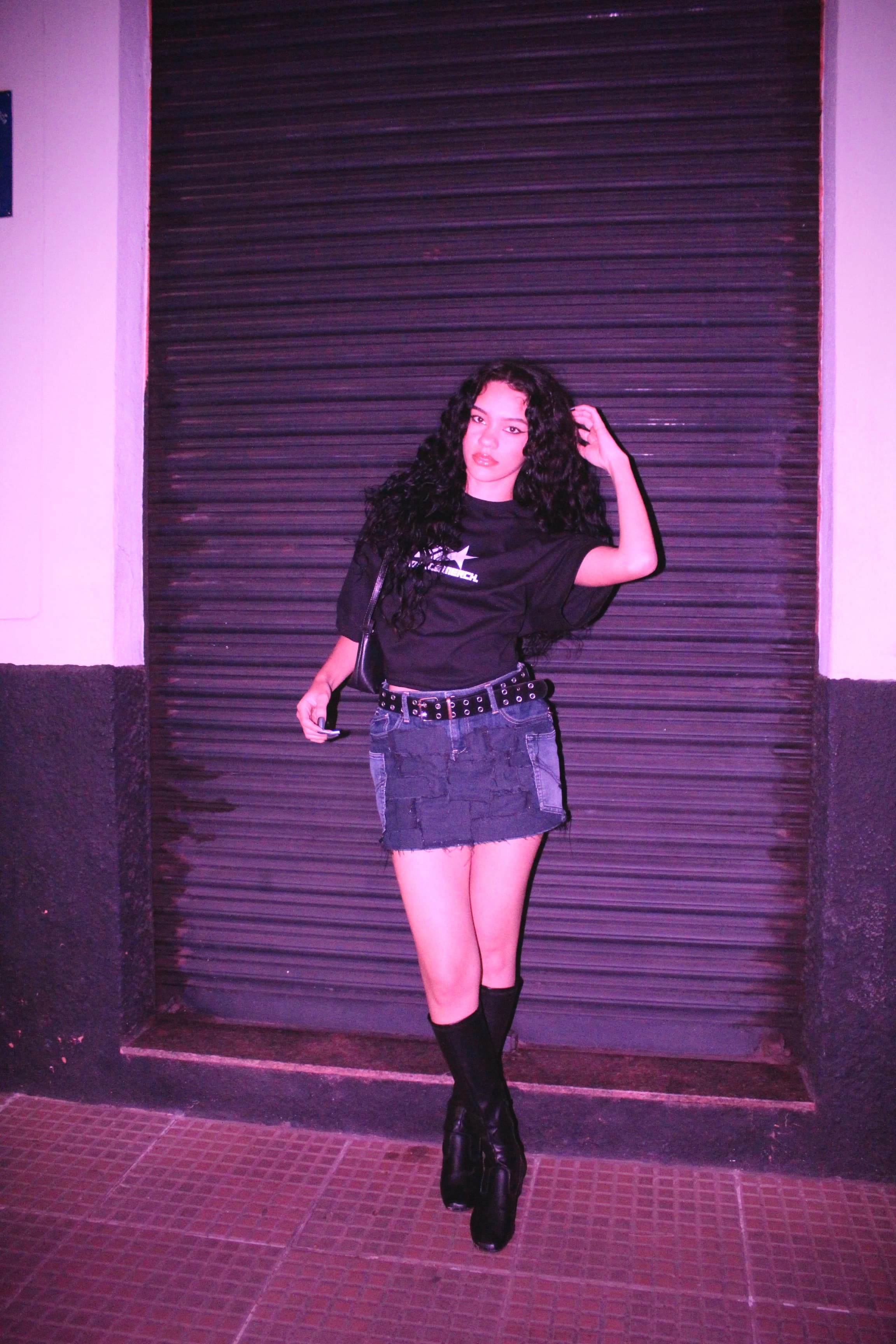 mulher fazendo pose na frente de uma porta usando a camiseta escrito 'NOFACE MERCH' com o logo da marca 'NOFACE'